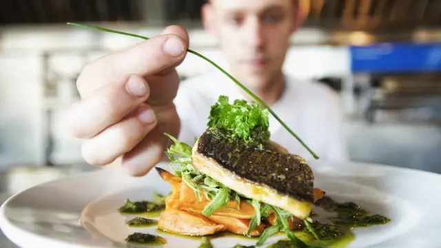 Un hombre decorando un plato.