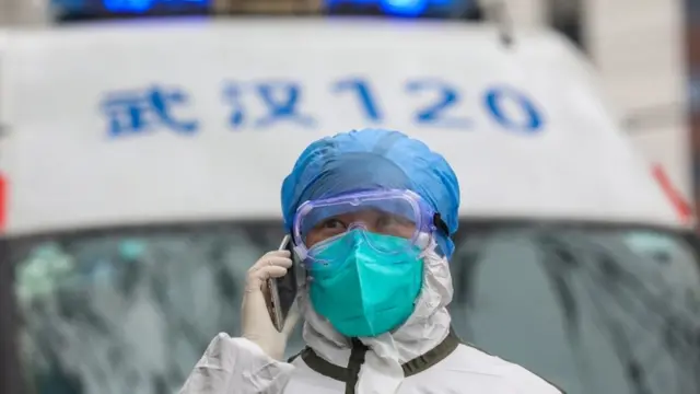 A fully protected nurse takes a phone call beside her ambulance in Wuhan, Hubei province, China