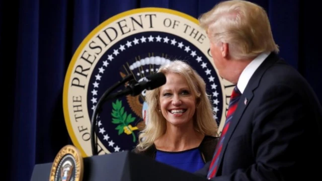 Trump no púlpito, olhando para Conway, que sorri para ele