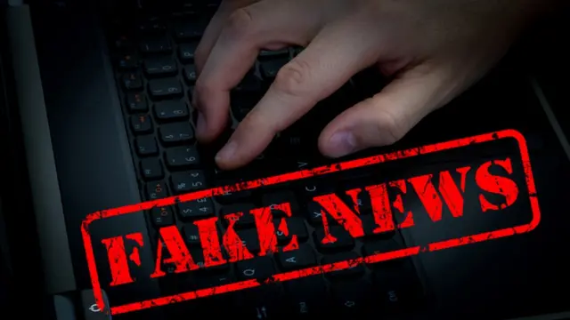 Mão dgitando em teclado com carimbo fake news