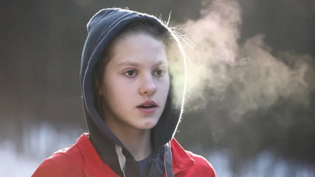 Una joven respira y se observa su aliento por el frío.