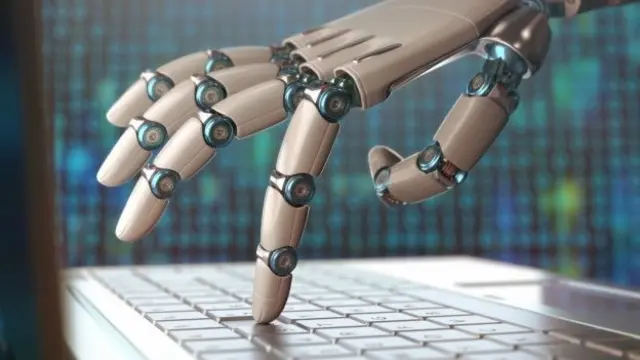 Robot escribiendo en computadora.