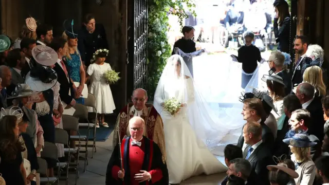 Noiva entra na capela, com crianças carregando a calda do vestido