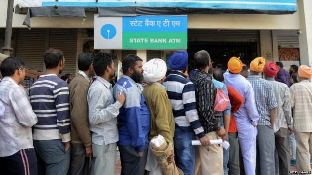 People wait to exchange banknotes in Amritsar, India