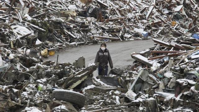 Un mujer camina entre los escombros en el pueblo japonés Minamisanriku, en el norte de Japón, tras el tsunami de 2011.
