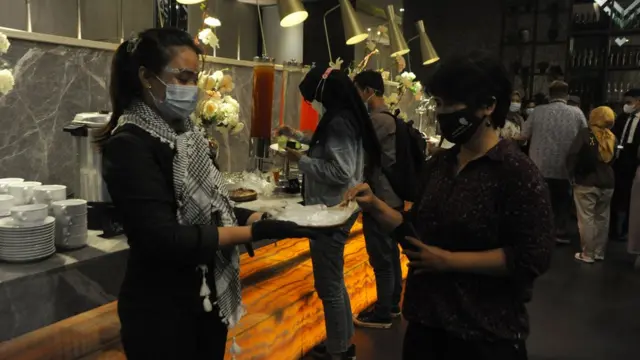 Petugas hotel memberikan sarung tangan plastik bagi pengunjung salah satu restoran hotel di Palembang, Sumatera Selatan, Selasa (13/04).