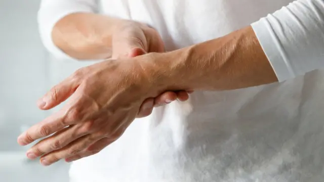Femme tenant son autre poignet d'une main pour soulager la douleur