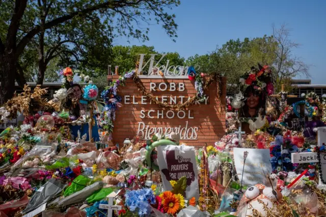 Ofrendas ante el cartel del Robb Elementary School de Uvalde, Texas.