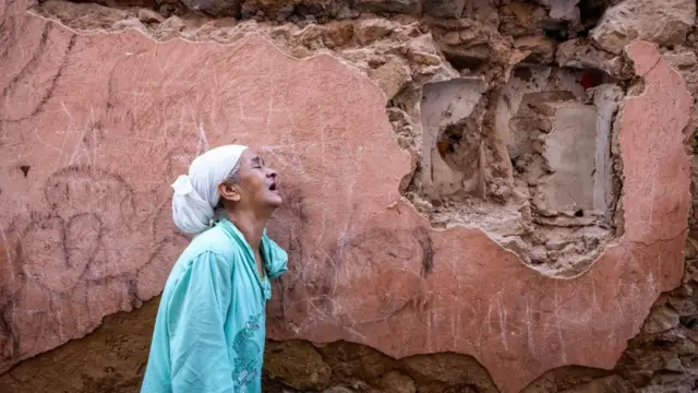 سيدة متأثرة تقف أمام منزلها المتضرر من الزلزال في المدينة القديمة في مراكش