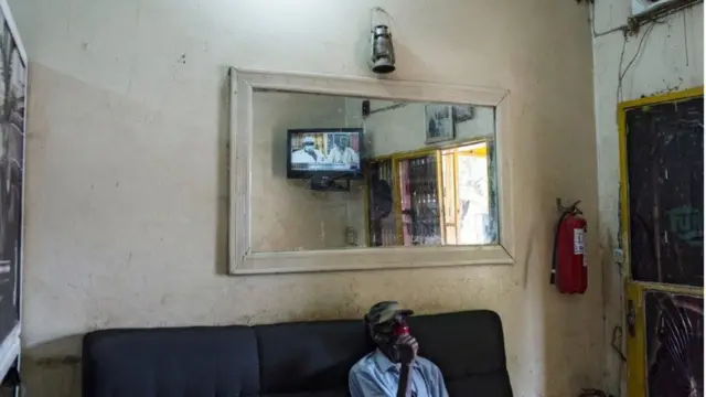 Un homme regarde la télévision locale pour voir la démission du président malien Ibrahim Boubacar Keita dans une imprimerie près du monument de l'indépendance à Bamako, au Mali.