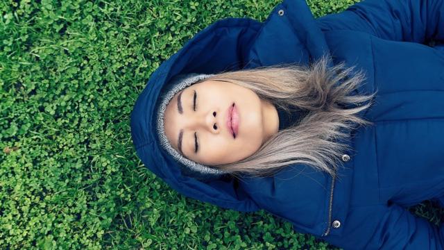 Young woman in a blue coat sleeping on a meadow