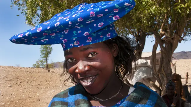 Joven mujer Herero con un colorido vestido y sombrero típico de parte superior muy ancha en tela estampada