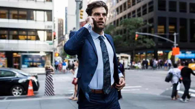 Un ejecutivo hablando por celular mientras cruza una calle