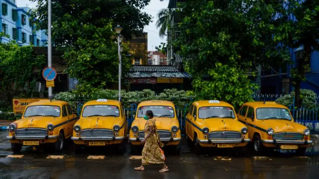 কলকাতায় এক সাড়ি হলুদ ট্যাক্সির সামনে দিয়ে একজন নারী হেঁটে যাচ্ছেন, ২০-০৮-২০২০।