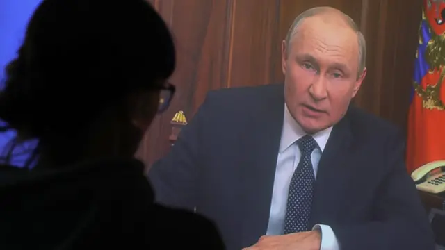 Una mujer ve un discurso de Putin en televisión