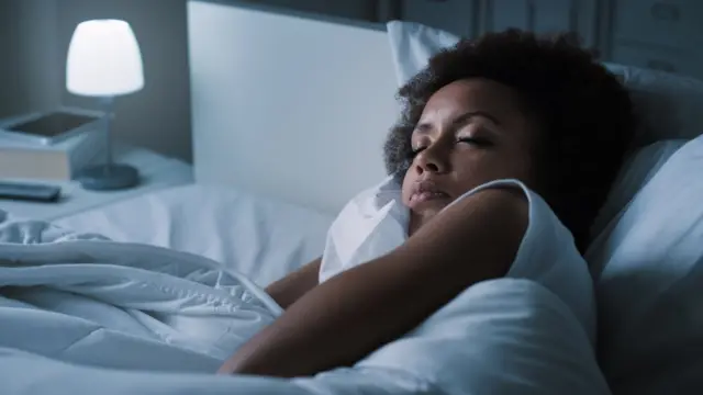 Mujer durmiendo en la cama con luz tenue.