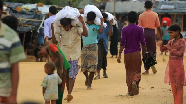 Para pengungsi yang terdaftar resmi mengambil jatah beras dari gudang yang dijalankan oleh badan-badan PBB