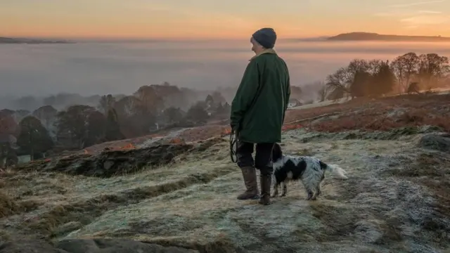 Mullher passeando com cachorro ao nascer do sol