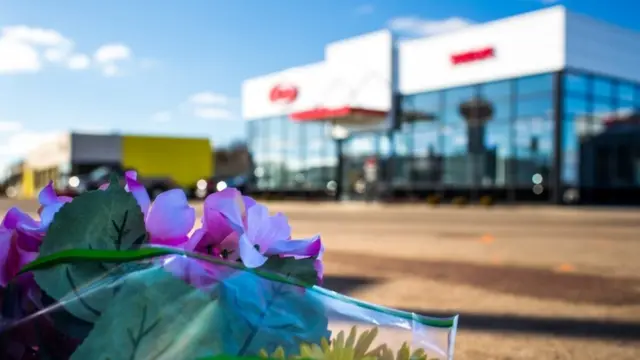 父親と息子が犠牲になった自動車販売店の前に花が手向けられた