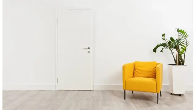 Un sofá amarillo y una planta en un espacio mayormente blanco