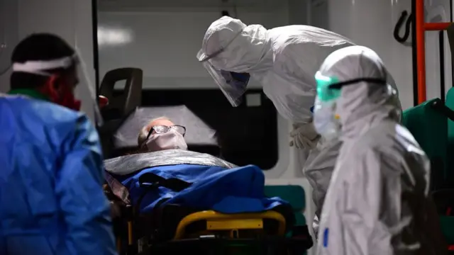 Médicos totalmente cubiertos con un paciente con tapabocas.