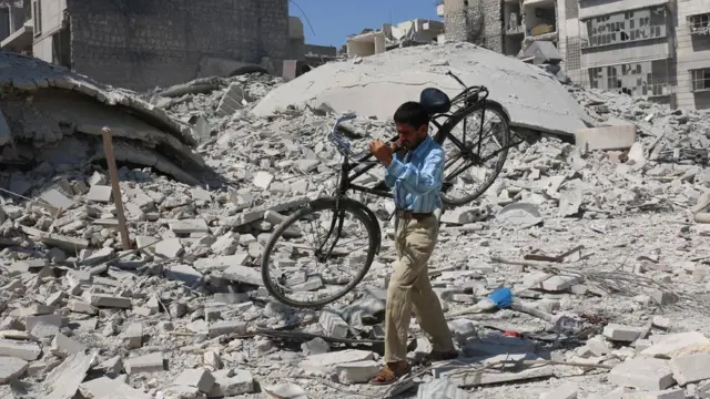 Halep'te muhaliflerin kontrolündeki Salihin'de bir kişi bisikletini taşıyor.