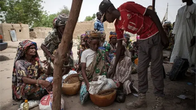A member of Civilian Joint Task Force (CJTF) screens women at the entrance of the town of Damasak in North East Nigeria