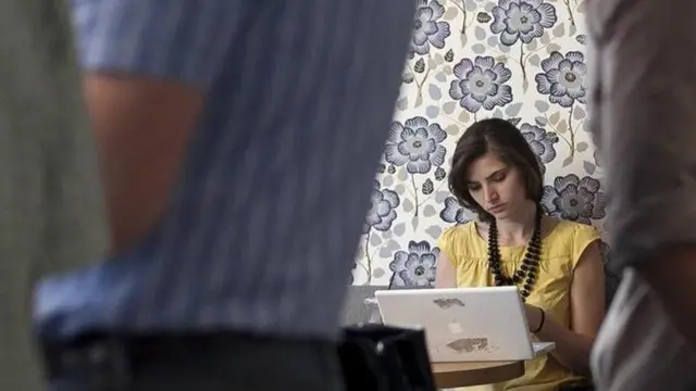 سيدة تعمل في أحد المقاهي على كمبيوتر شخصي