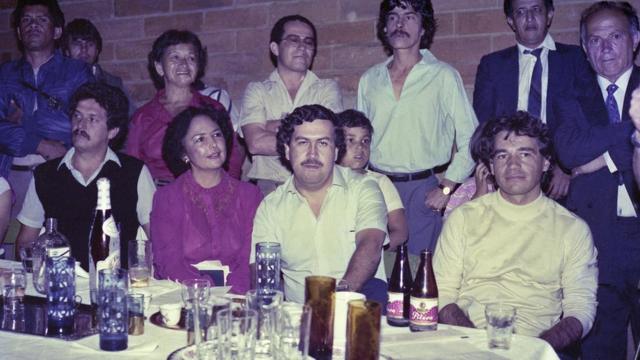 Escobar, com Carlos Ledher (cofundador do Cartel de Medellín, dir.) e uma líder local (esq.) em agosto de 1983, ao inaugurar a iluminação de um dentre dezenas de campos de futebol reformados e iluminados por ele
