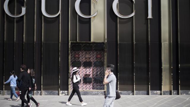 People walk next to a store of Italian luxury brand Gucci on the fourth ring road in Beijing