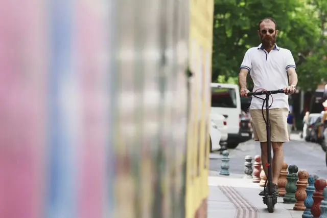 Homem pilotando um patinete elétricosportingbet tem pagamento antecipadouma calçada