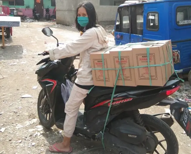 Yuni Sri Rahayu mengantarkan makanan kripik bawang ke pelanggan.