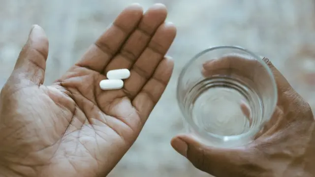 Woman holding aspirin tablets in her hand