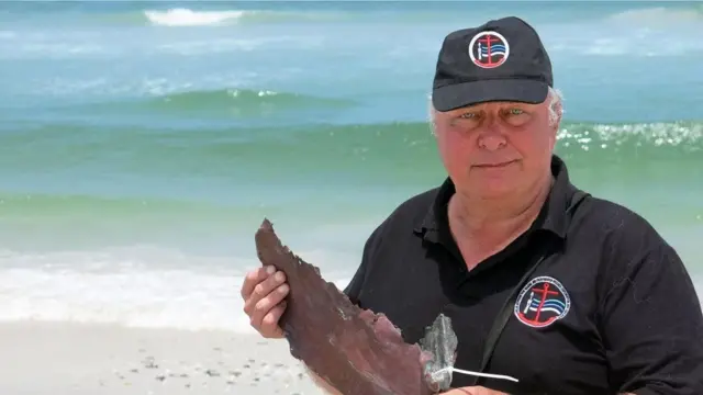 برونو ويرز يحمل قطعة من النحاس يرجح أنها من بقايا دفة سفينة نيو هارلم