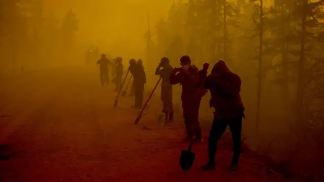 Trabajadores se cubren ante el humo por los incendios en Yakutsk, Rusia.