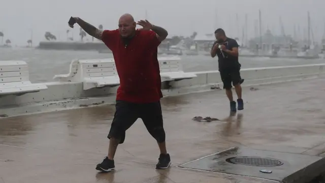 Dos personas caminando pese a los fuertes vientos y la lluvia en Corpus Christi