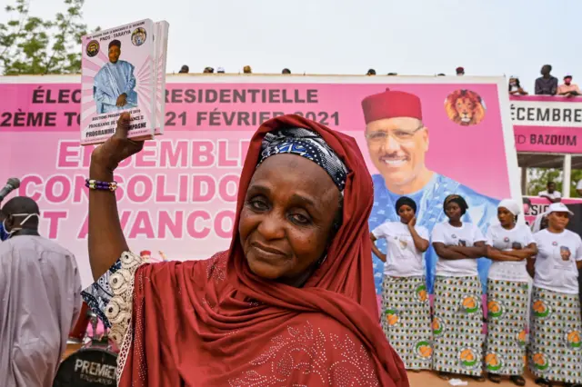 A woman hoisting an election campaign poster of Mr Bazoum.