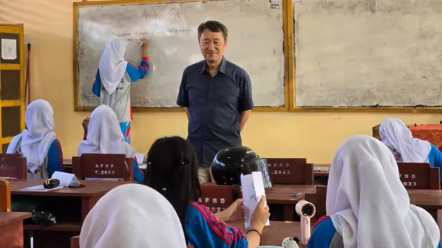 Jung Deuk Young berdiri di depan kelas saat mengajar aksara Hangeul di sebuah sekolah di Buton Selatan.