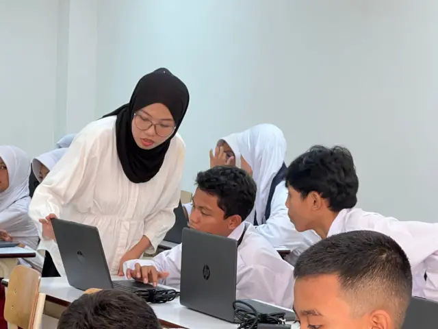 Seorang guru di Sekolah Rakyat yang berada di Sentra Handayani, Jakarta sedang memandu seorang siswa menggunakan learning management system.