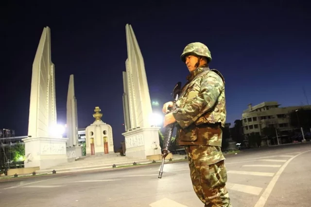 ทหารยืนประจำการบริเวณอนุสาวรีย์ประชาธิปไตยในคืนวันที่ 22 พ.ค. 2557 หลัง พล.อ.ประยุทธ์ จันทร์โอชา ผบ.ทบ. ในขณะนั้น กระทำการรัฐประหารและประกาศเคอร์ฟิวซึ่งมีผลตั้งแต่เวลา 22.00 น. ของวันเดียวกัน