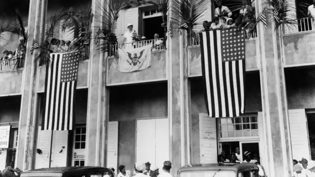 ఒక భవనంపై అమెరికన్ జెండాలు మరియు ఎలియనోర్ రూజ్‌వెల్ట్