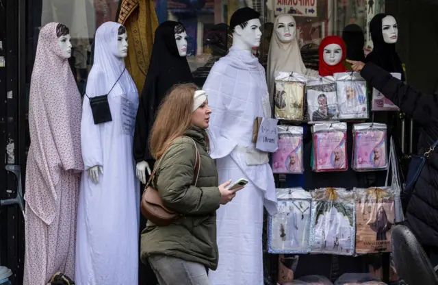 Žena prolazi pored prodavnice u kojoj se prodaje hidžab