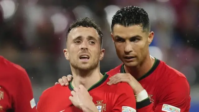 bir maç sırasında ronaldo jota'nın arkasında, omuzlarını tutmuş.