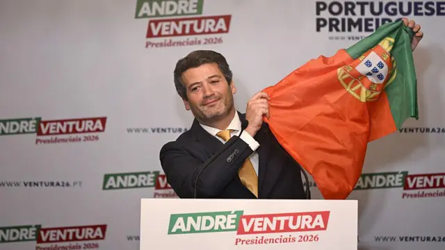 André Ventura levantando uma bandeira de Portugal. 