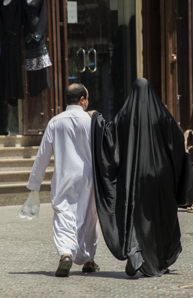 Una pareja saudita camina por las calles de Al Balad, están vestidos con la vestimenta tradicional.