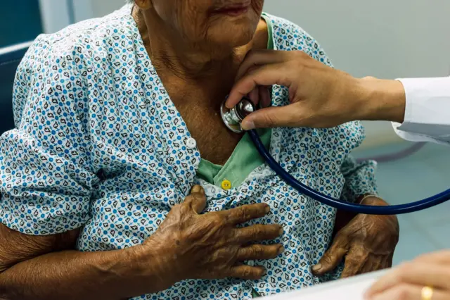 Male Doctor listening heart beat and breathing of Elderly Woman with Stethoscope with First Aid Medical Box.Community Health and Development Hospital In Remote Areas Development Fund Concept.