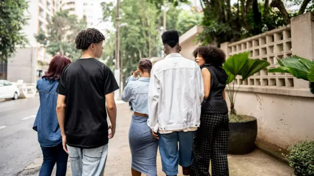 Friends dey tok while dey waka di street 