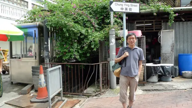 赵崇基在中英街港方路牌前拍照留念（赵崇基提供照片）