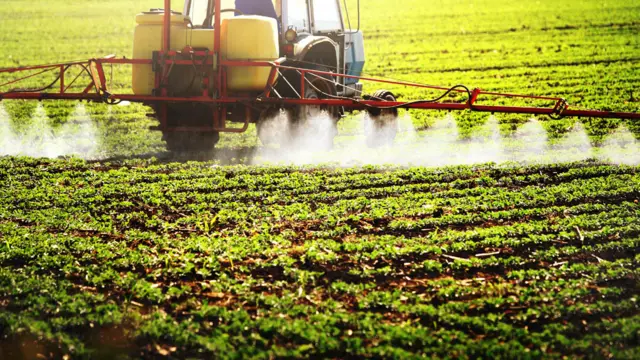 Vehículo rociando filas de plantas con plaguicida