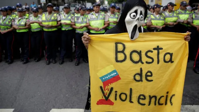 Un manifestante con un cartel de "Basta de Violencia".